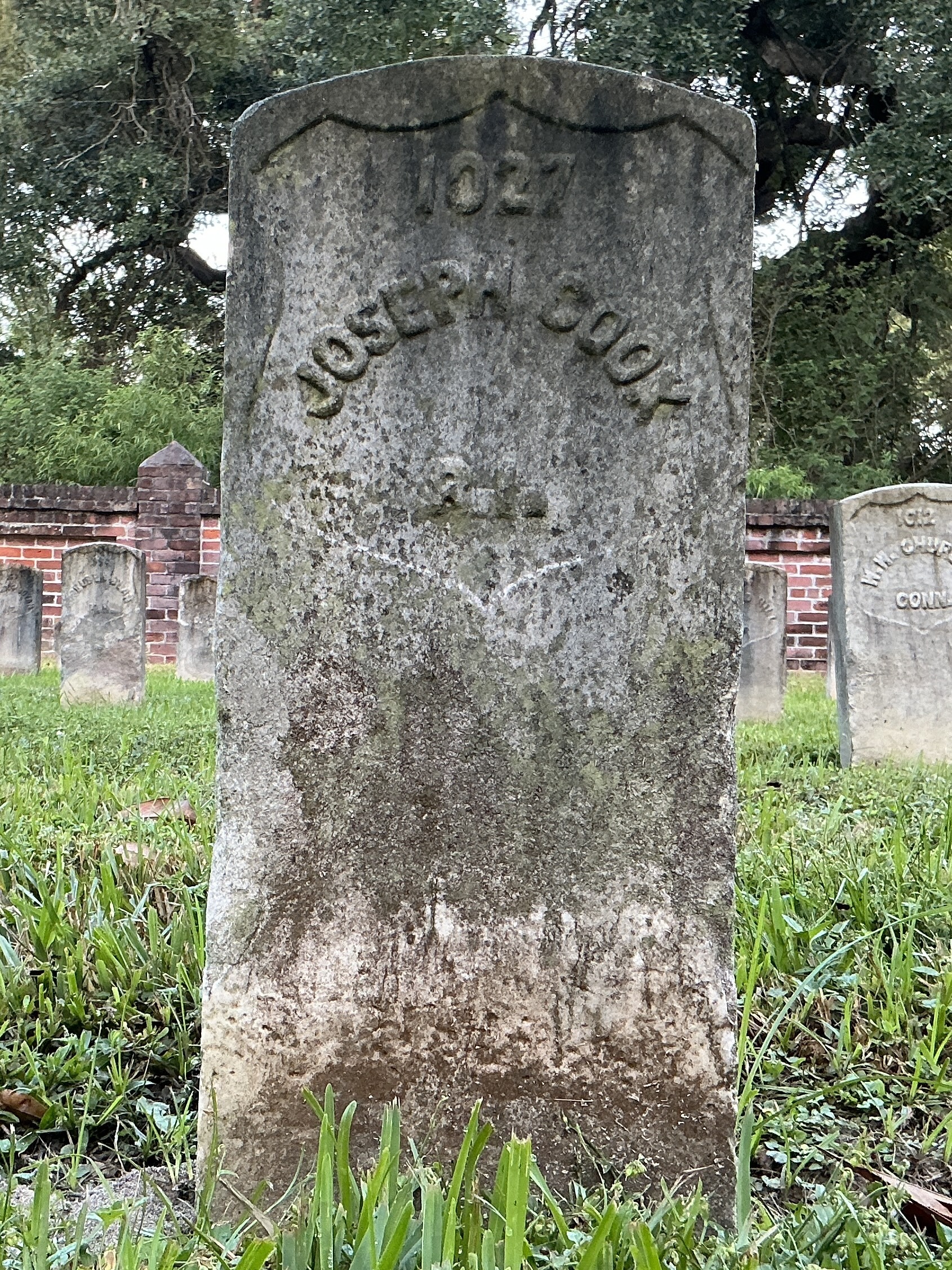 Front of historic upright marble headstone with recessed shield face.