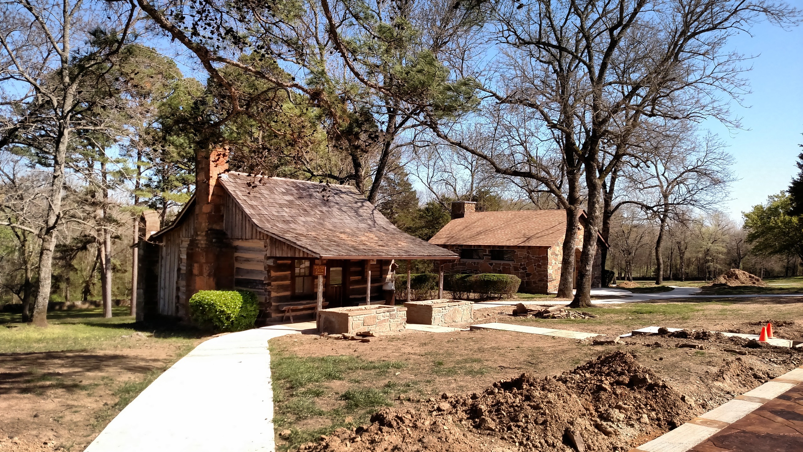 Two small log cabins sit in the middle of a wooded area.