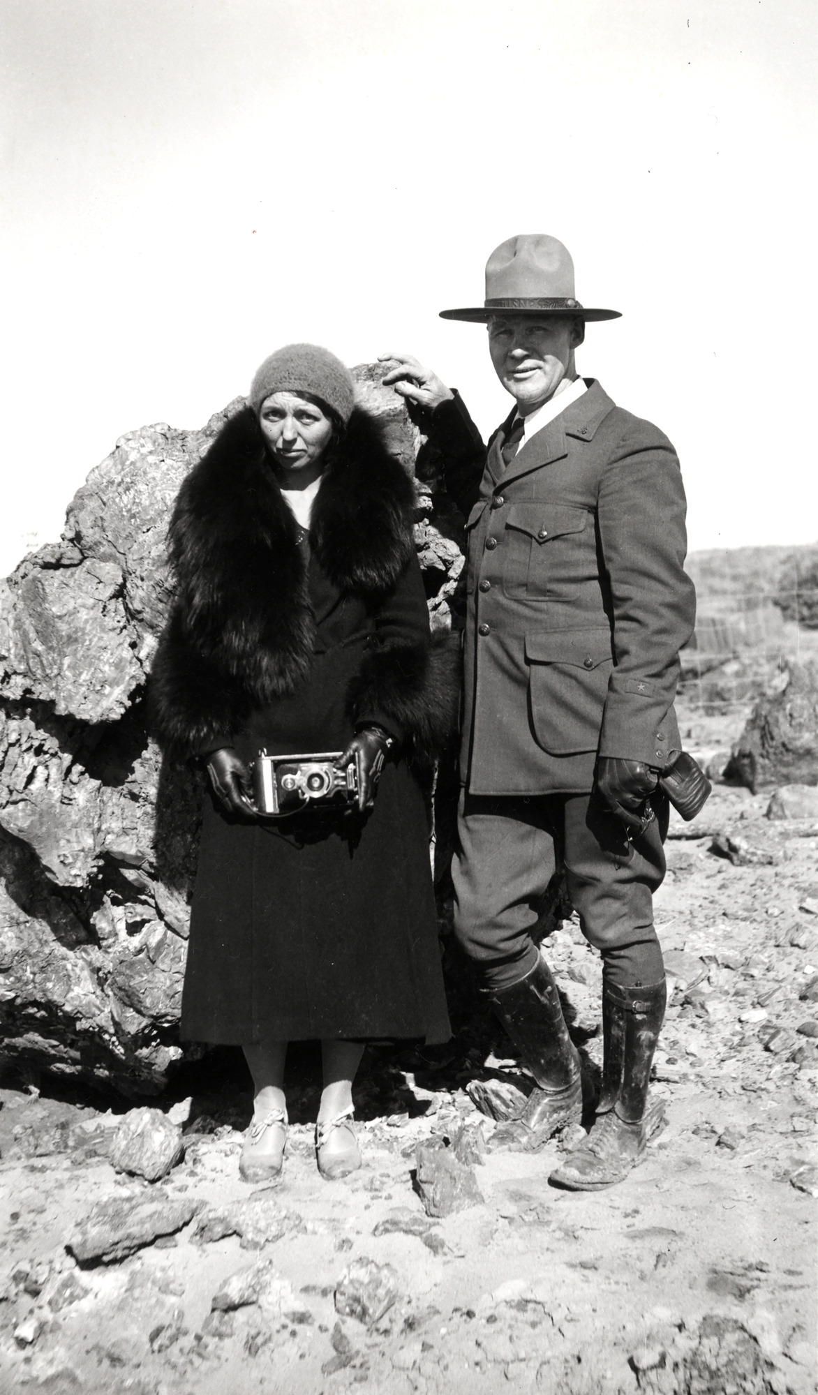 Dama Smith and her husband Charlesstand in front of a large piece of petrified wood. 
