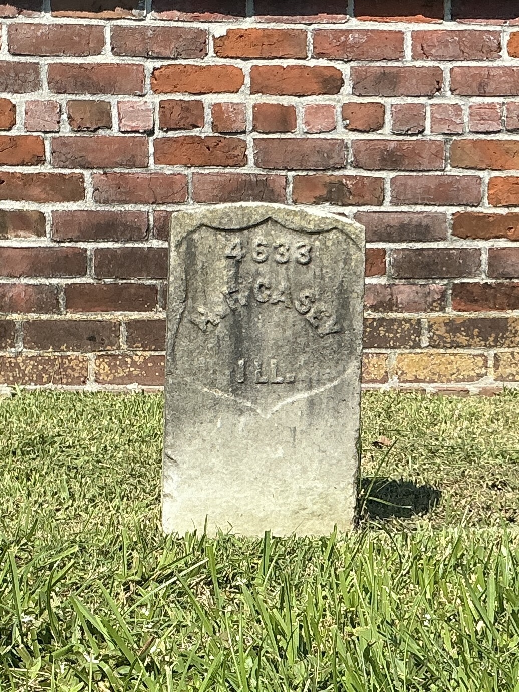 Front of historic upright marble headstone with recessed shield face.