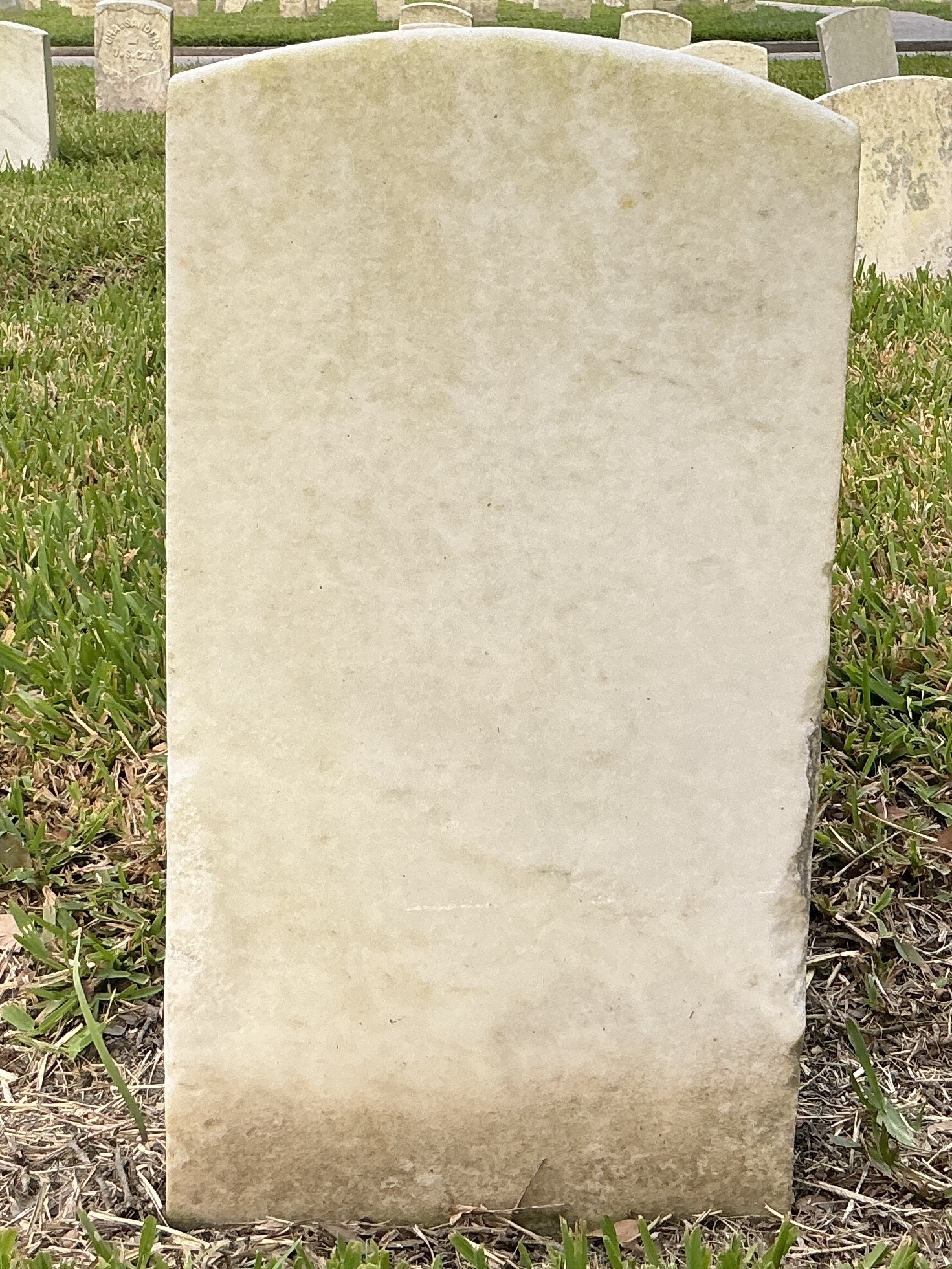 Back of historic upright marble headstone with recessed shield with recessed lettering face.
