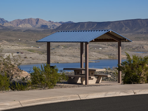 shade structure covering picnic bench, lake and hills in distance