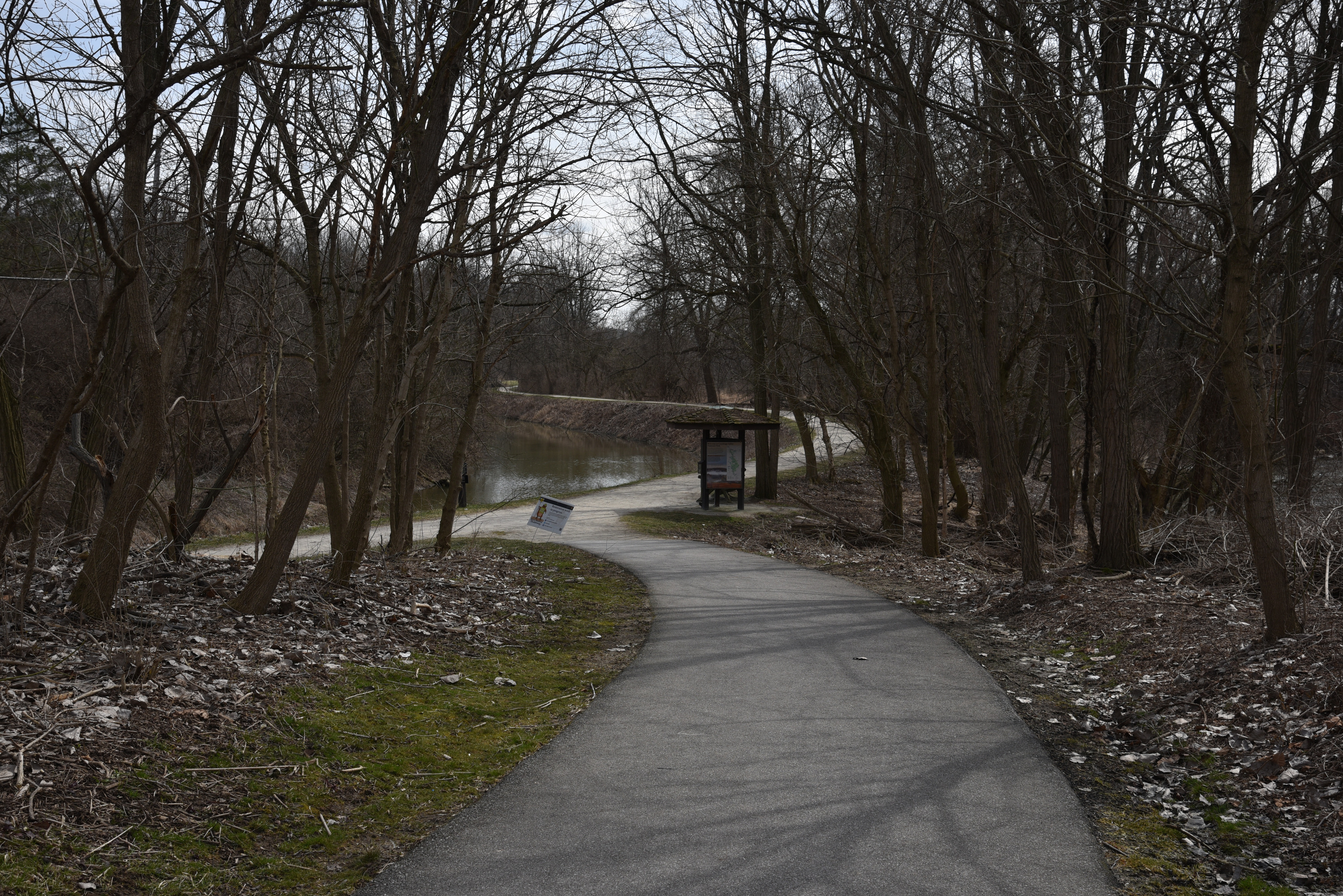 Paved path leads downhill to a triangular information kiosk.