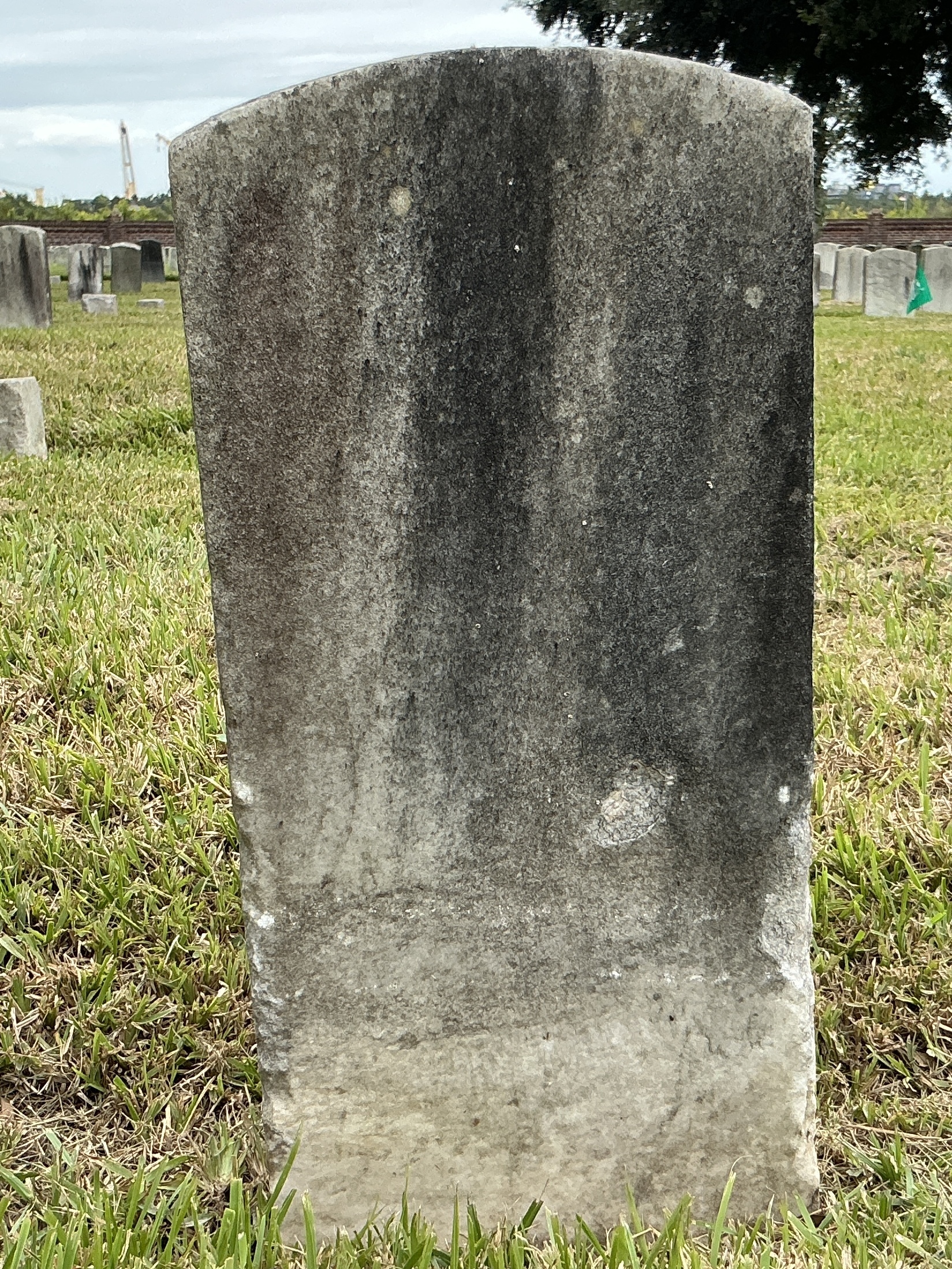 Back of historic upright marble headstone with recessed shield with recessed lettering face.