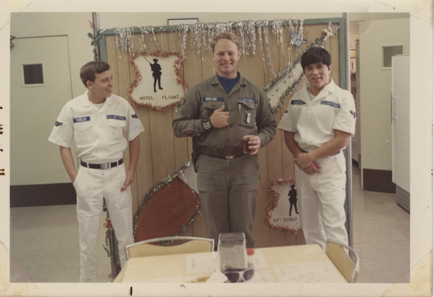 Uniformed airmen stand in front of a dining table with Christmas decorations behind