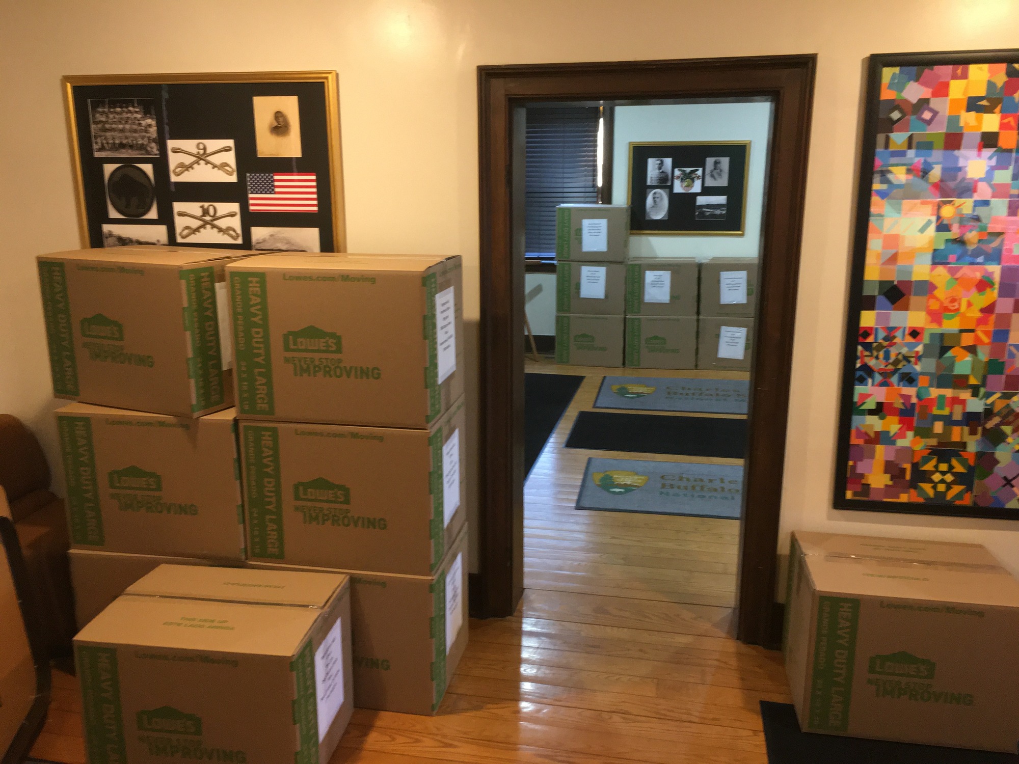 Boxes stacked and arranged along a wall next to a doorway.