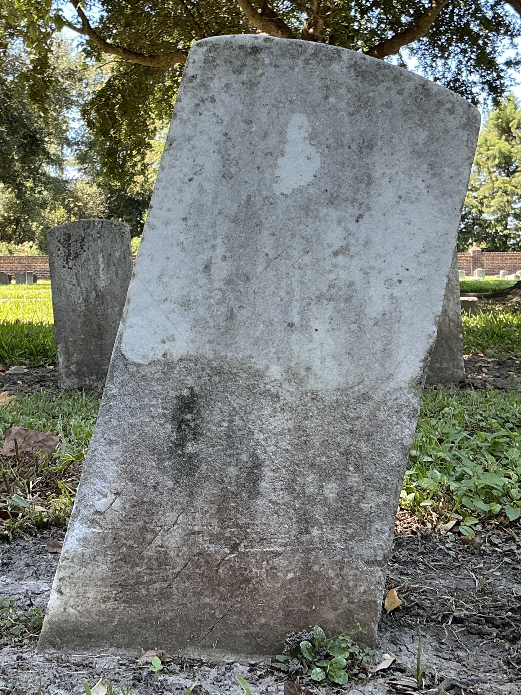 Back of historic upright marble headstone with recessed shield with recessed lettering face.