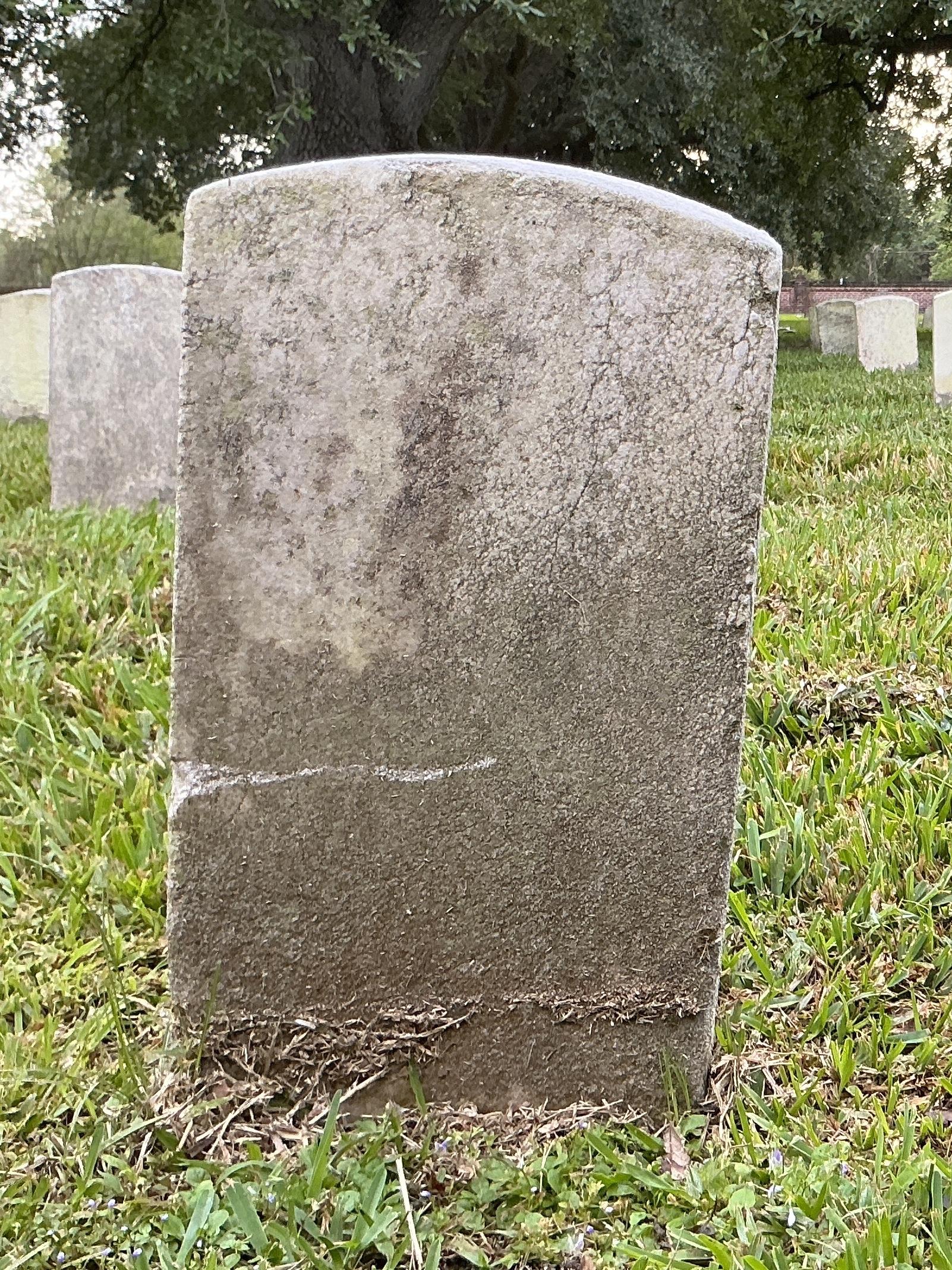 Back of historic upright marble headstone with recessed shield face.