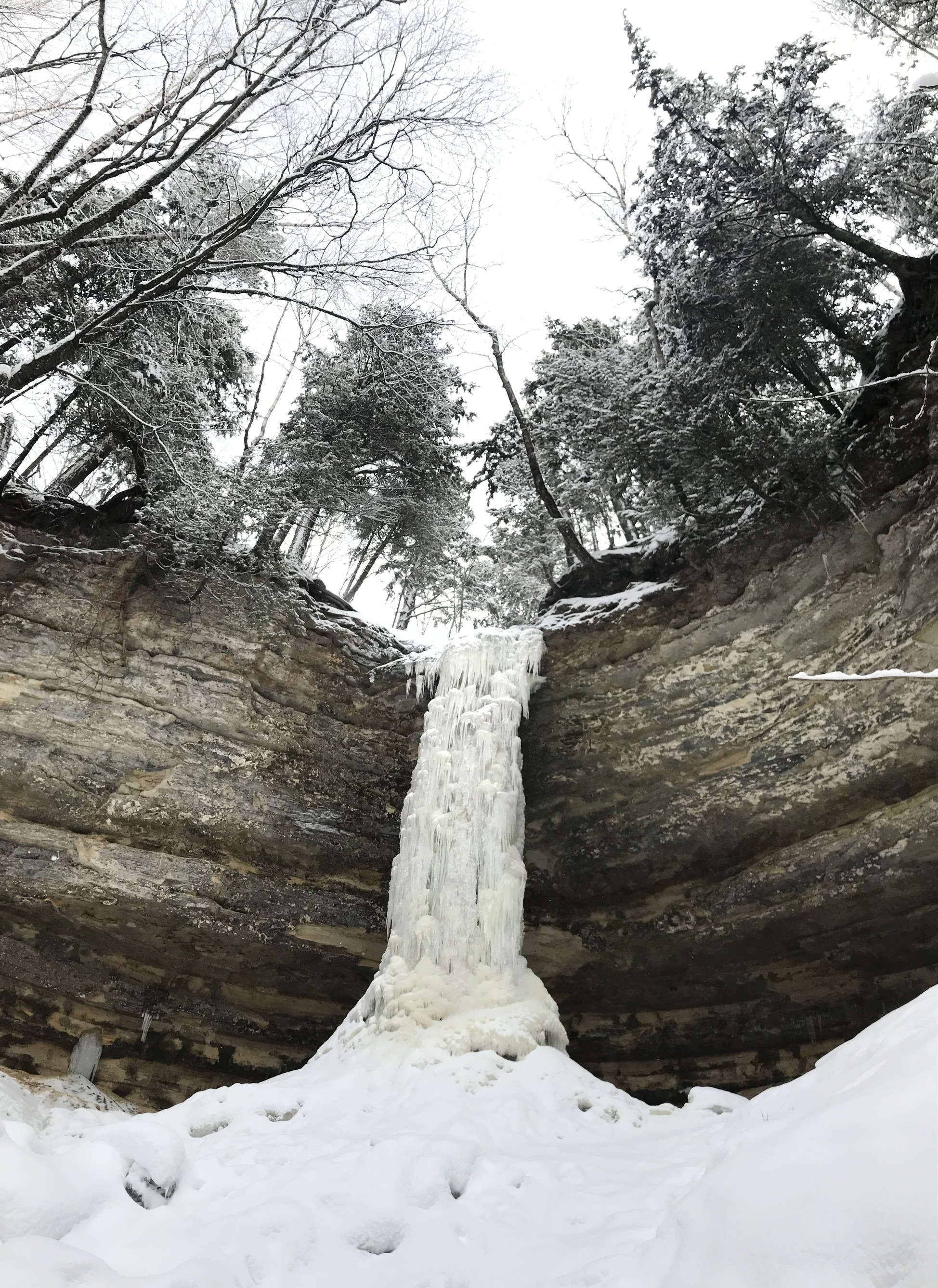 The frozen water flow is over 50 high and is roundish in shape - like a dryer hose. It's lined on either side with layered sandstone cliffs.