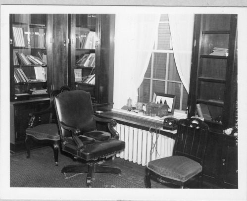 Leather desk chair with support cushions near a window in Franklin D. Roosevelt's study.  Leather chairs is flanked by two upholstered chairs.  Glass front bookcases containing some of the President's book collection.