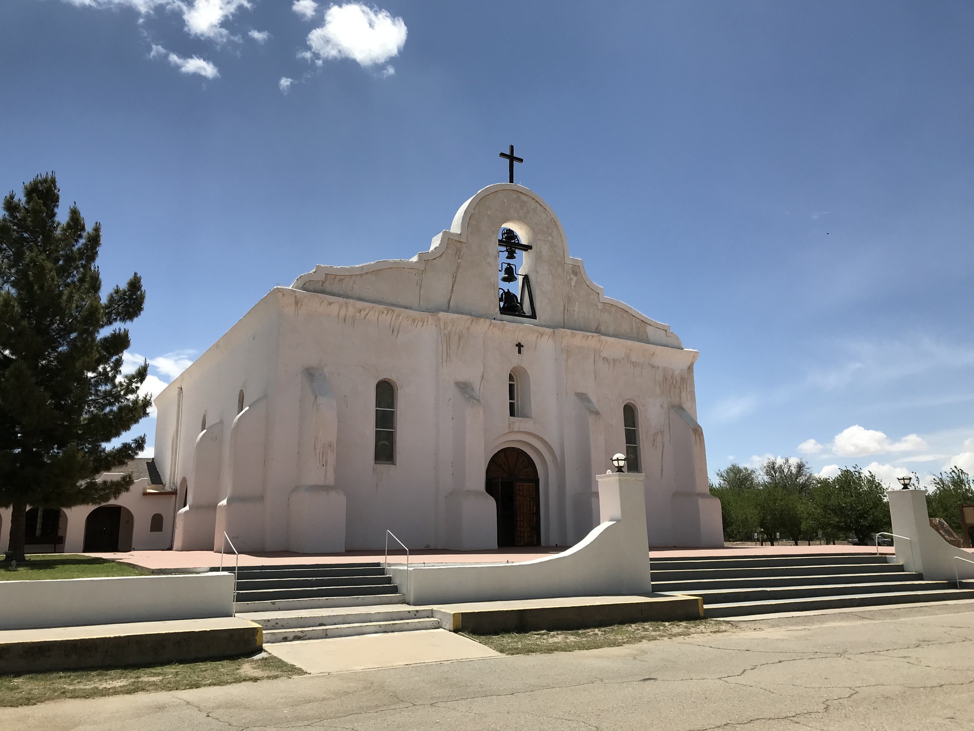 A white church with a cross in front of it.