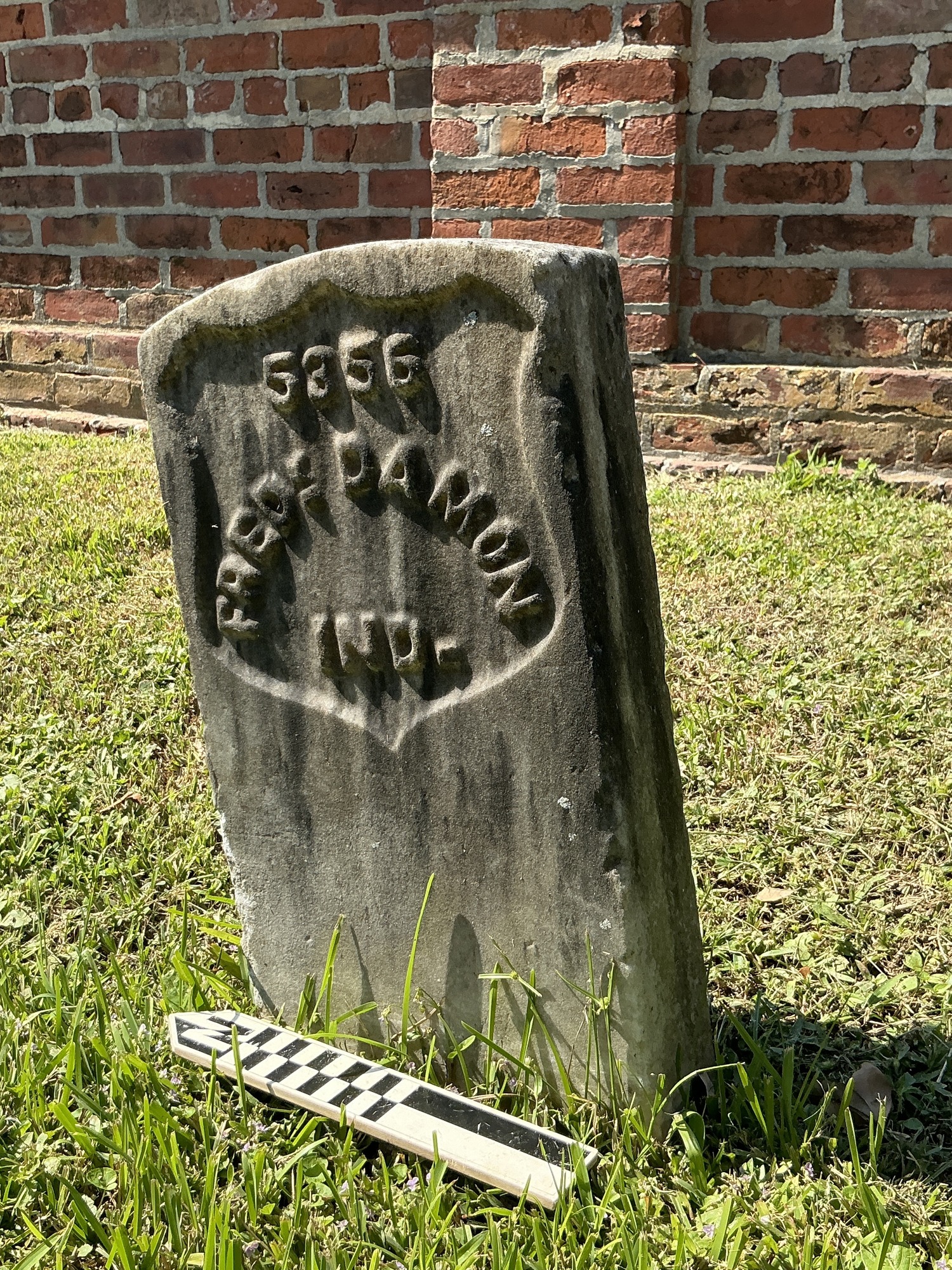 Back of historic upright marble headstone with recessed shield face.
