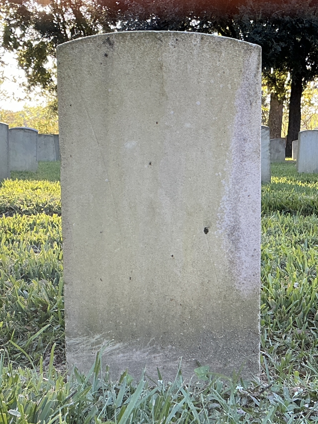 Back of historic upright marble headstone with recessed shield face.