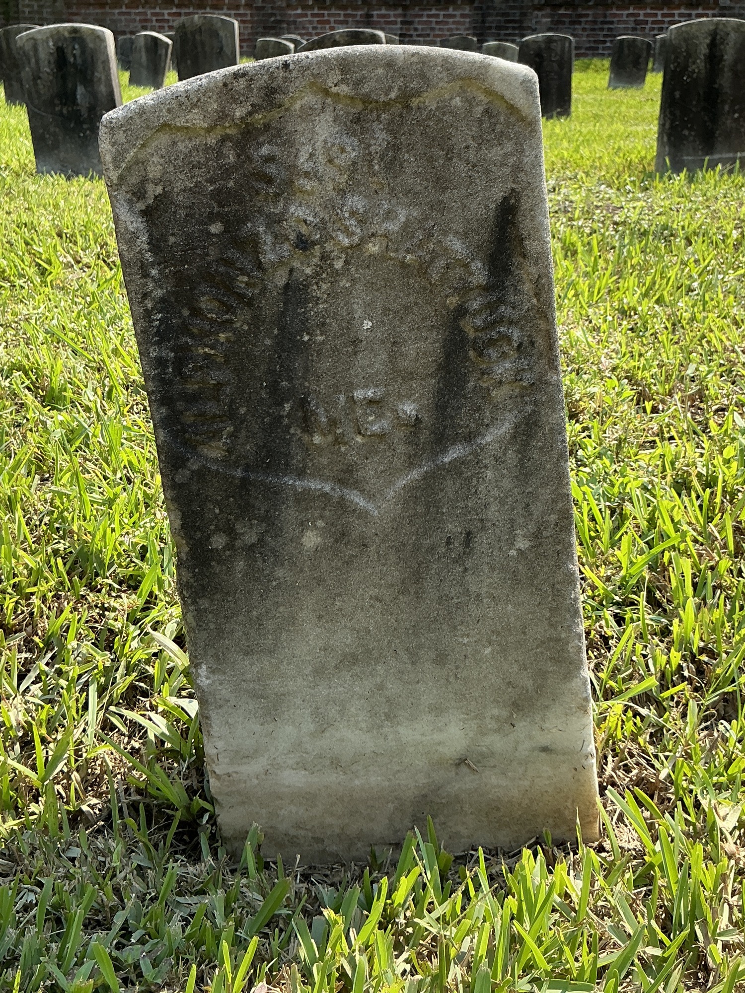 Front of historic upright marble headstone with recessed shield face.