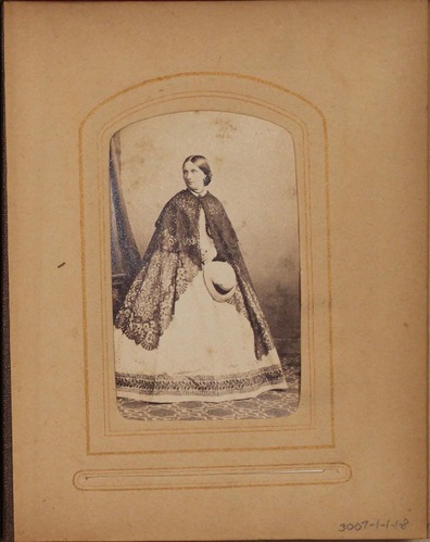 Black and white photograph of woman holding hat.