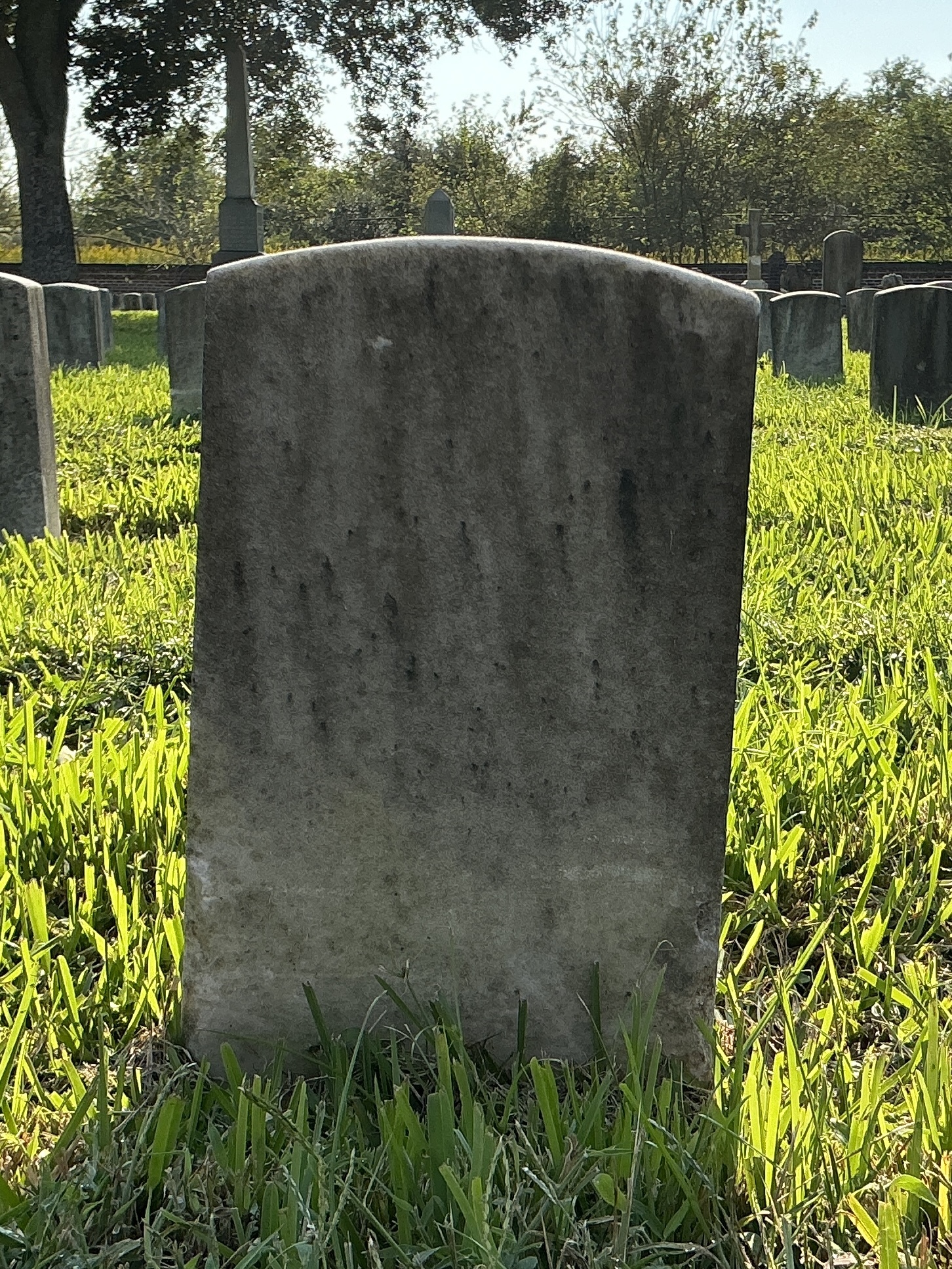 Back of historic upright marble headstone with recessed shield face.