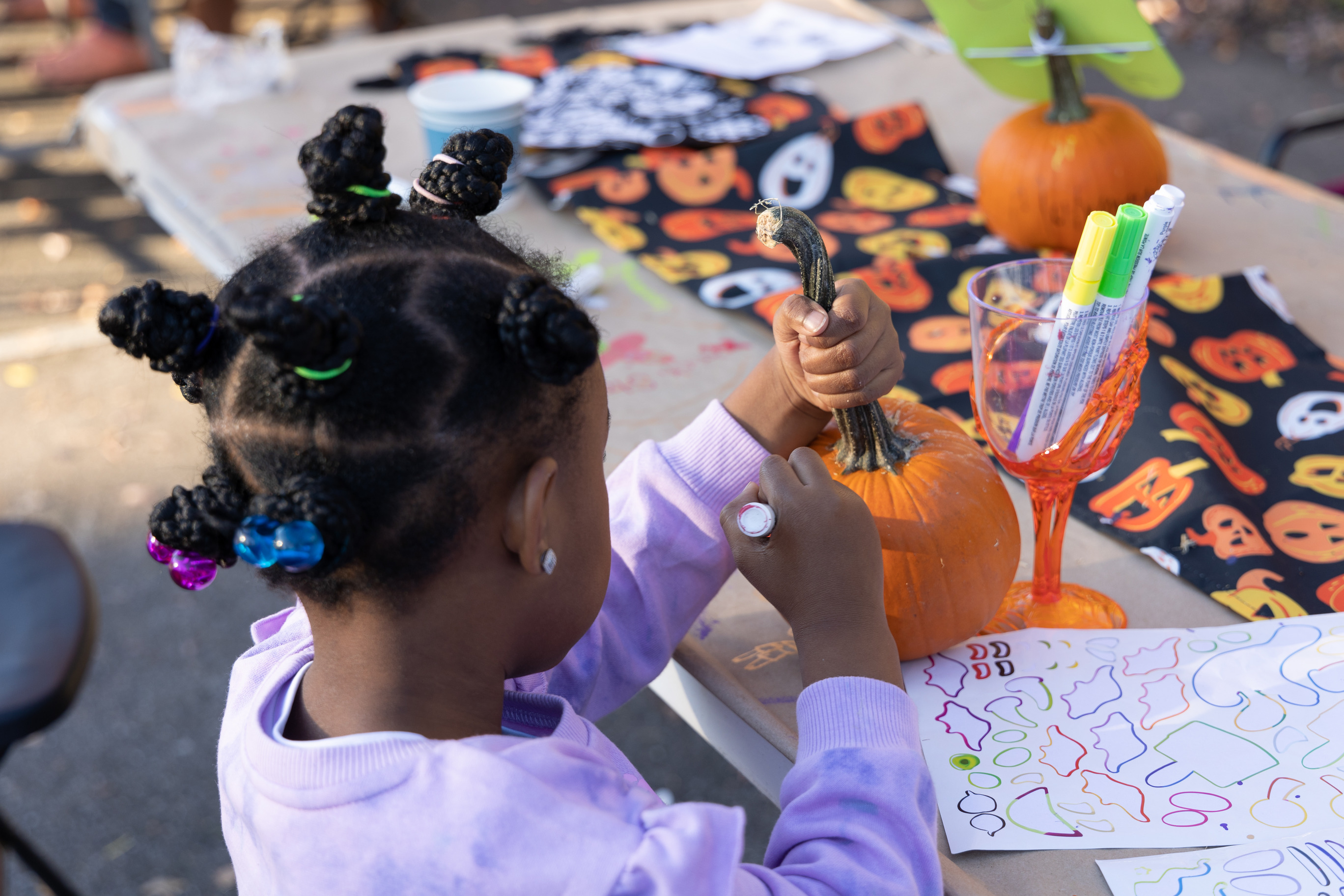 A child decorates a pumpkin at a Halloween event.