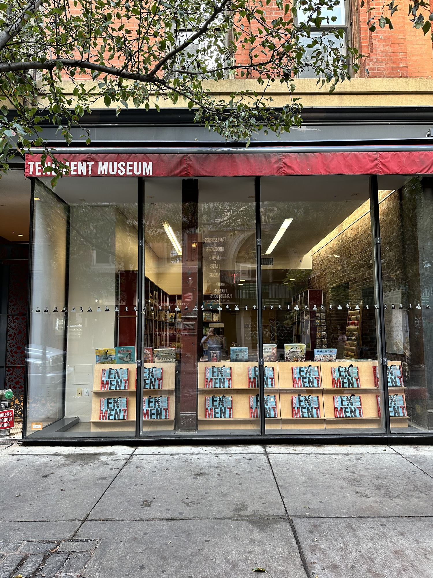 A building with floor to ceiling glass windows. A sign reads Tenement Museum. 