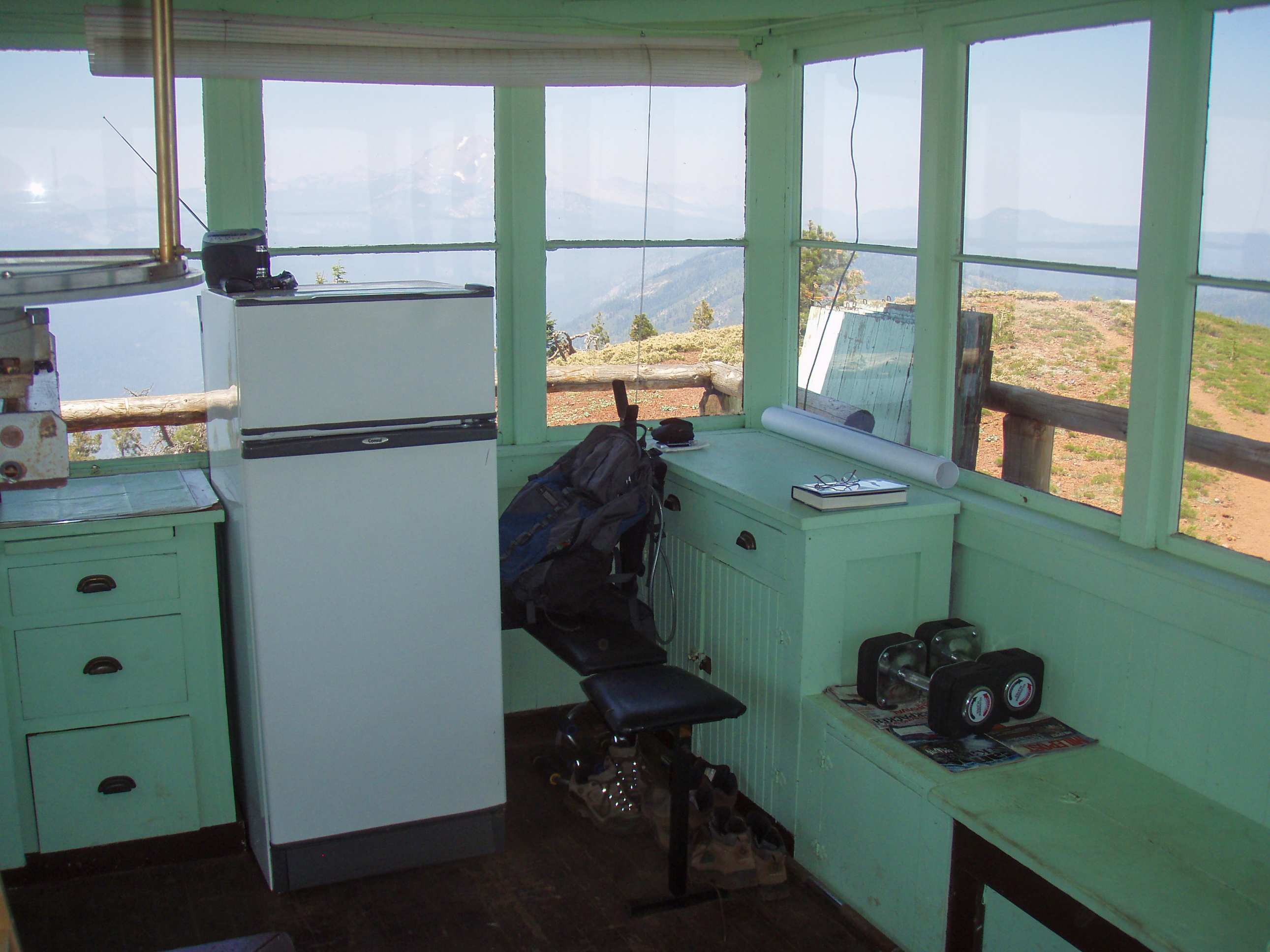 A fridge and cabinets inside a wooden fire lookout tower.