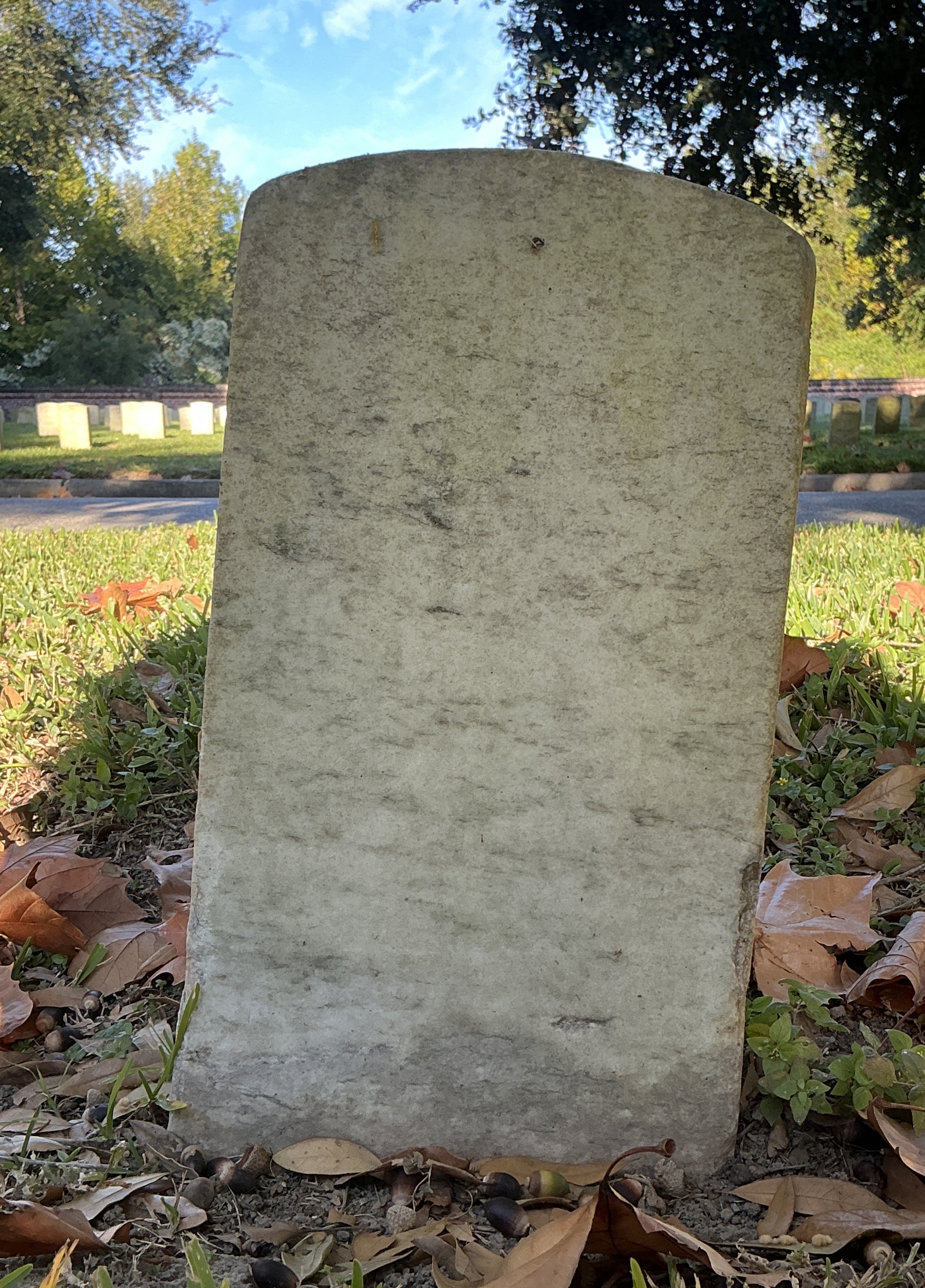 Back of historic upright marble headstone with recessed shield face.