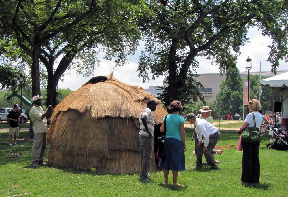 wooden dome frame is completely covered in grass, visitors are admiring it