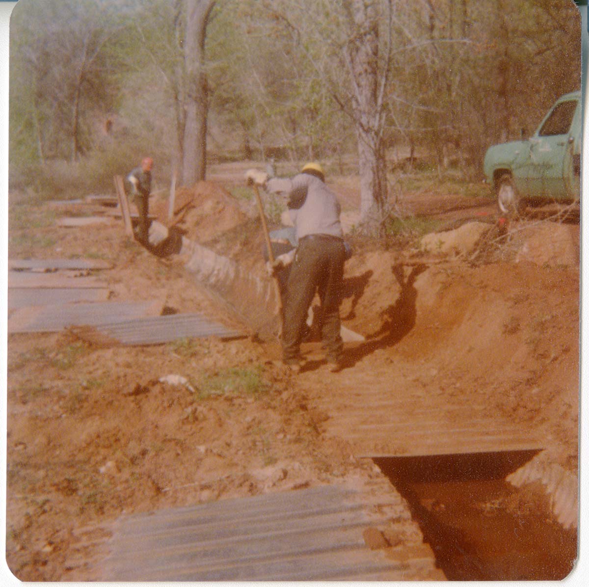 Men digging and working to uncover the irrigation ditch in South Campground.