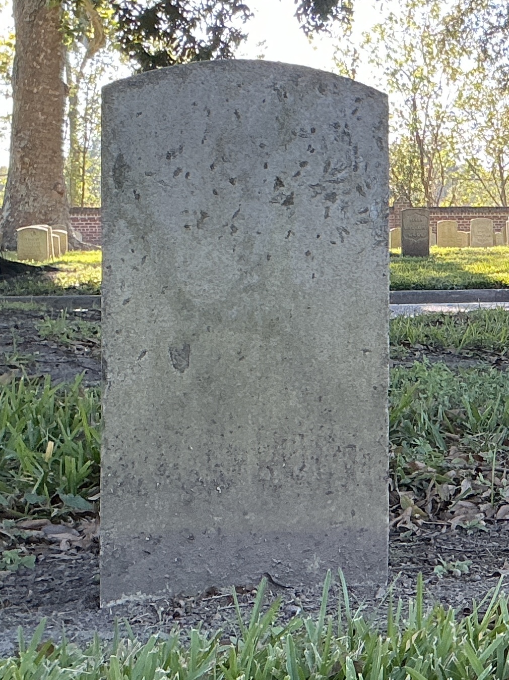 Back of historic upright marble headstone with recessed shield face.