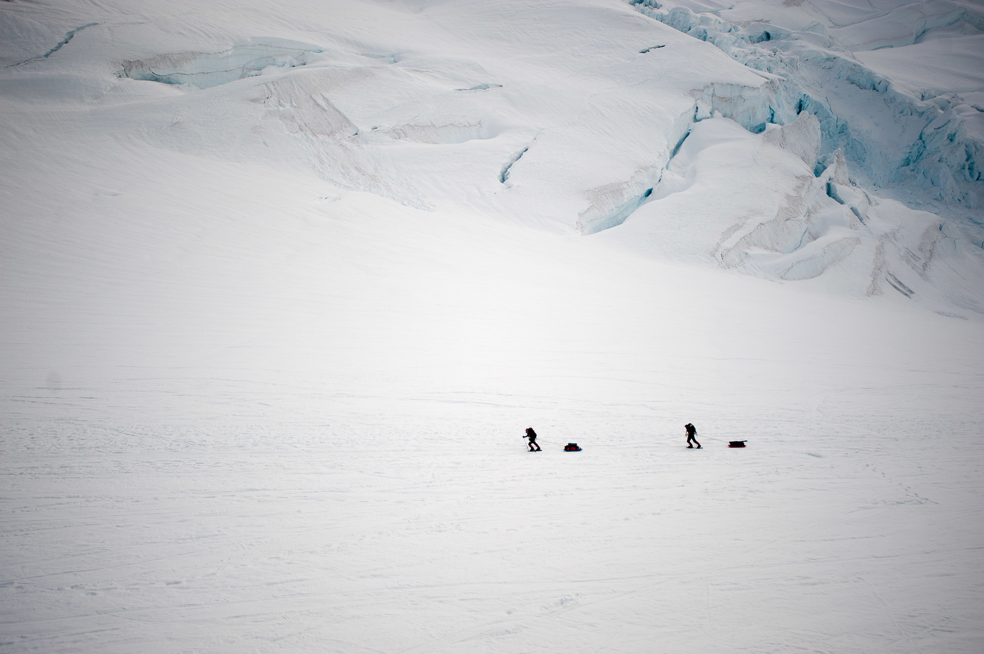 Two mountaineers pull sleds up-glacier 
