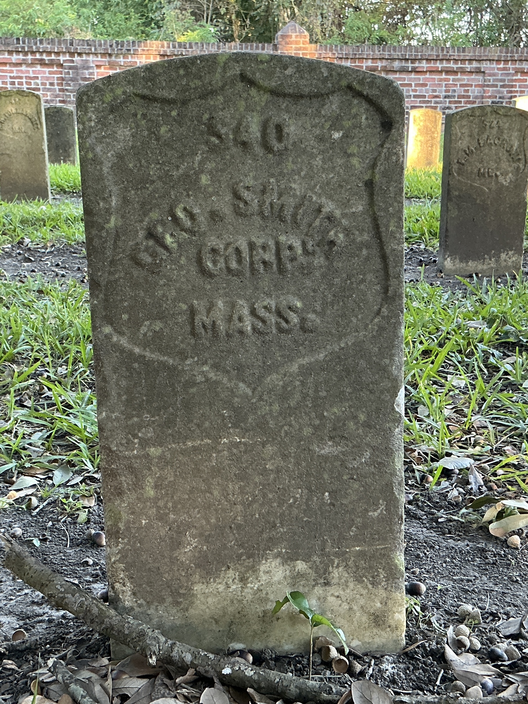 Front of historic upright marble headstone with recessed shield face.