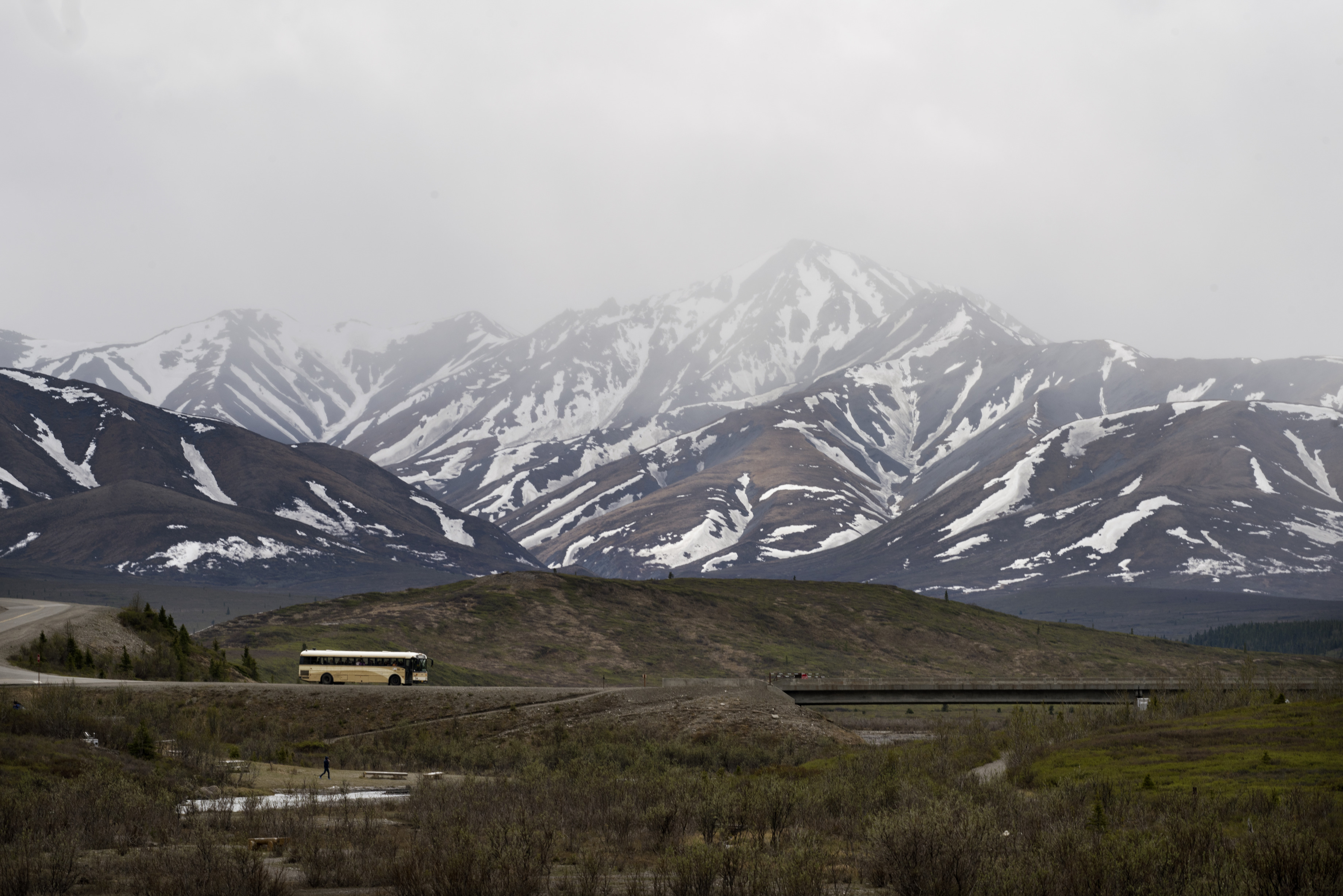 a bus driving on a paved road toward a short bridge