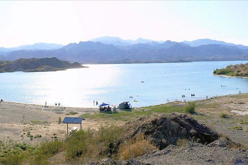 cove with pop-up tents and swimmers with mountains in the distance. 