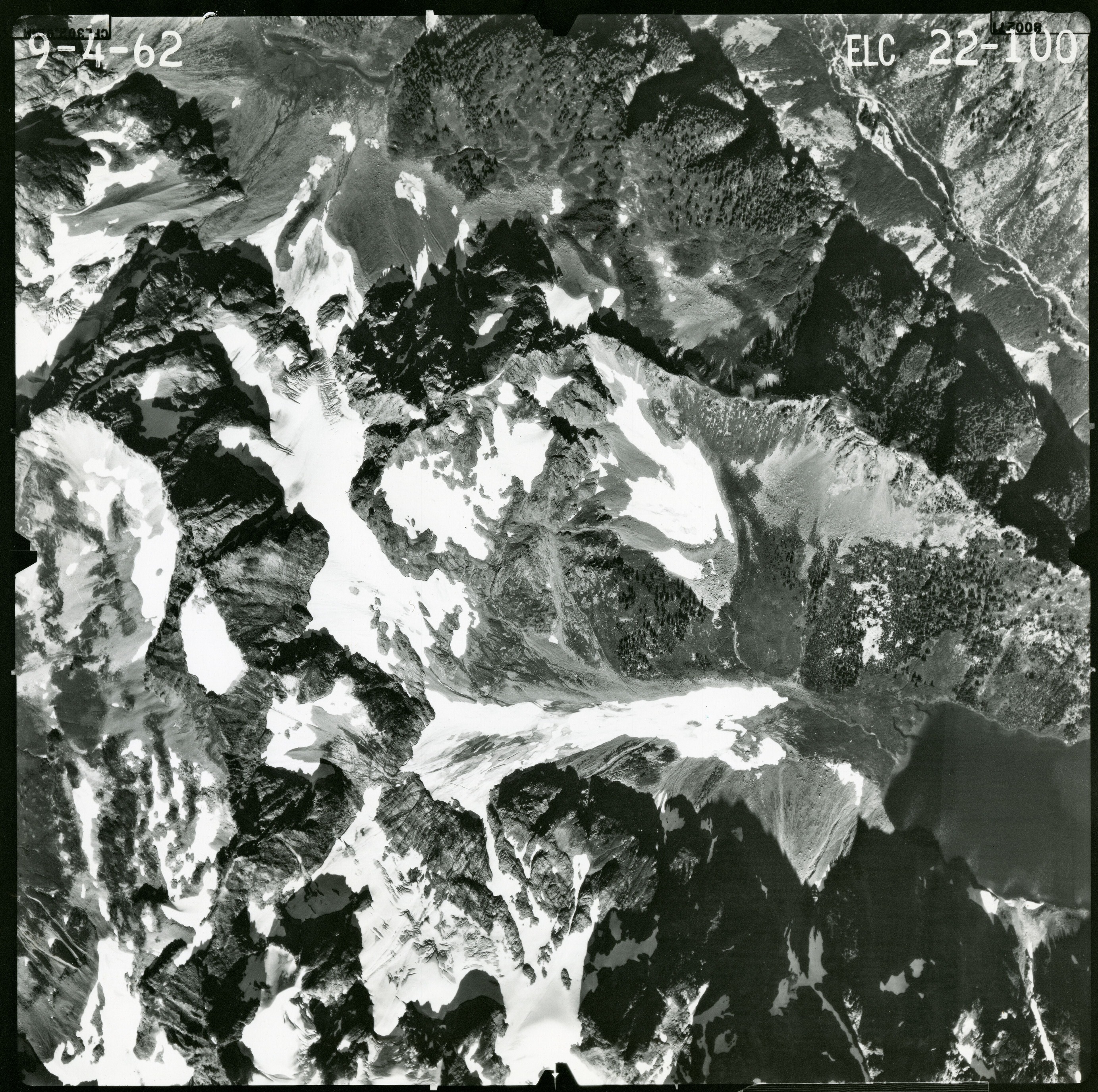 Black and white aerial photograph of glaciated mountain peaks and valleys.