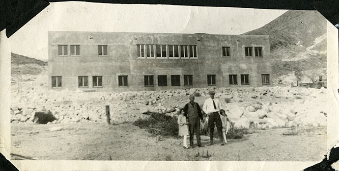 This is an historic black and white photograph from the Scotty's Castle Historic Photograph Collection, Death Valley National Park of Albert M. Johnson with unidentified man and two girls.  In front of  newly constructed Scotty's Castle Main House before second phase of construction / remodeling occurred. Circa 1922.