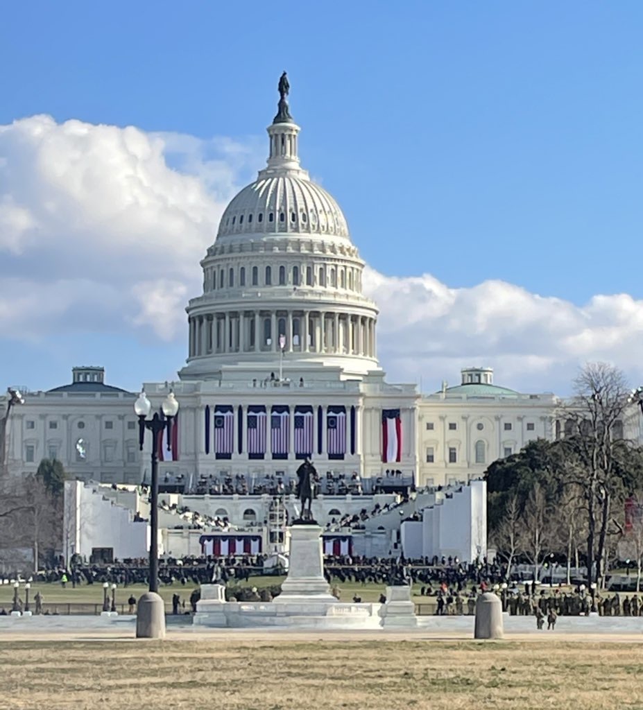 Military and police watching the U.S. Capitol building, which is decorated with U.S. flags and red, white, and blue banners