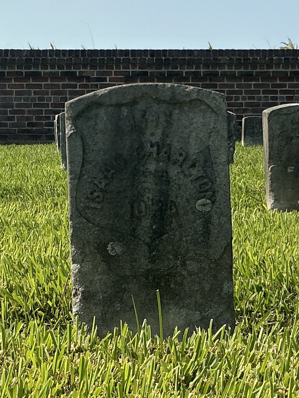 Front of historic upright marble headstone with recessed shield face.
