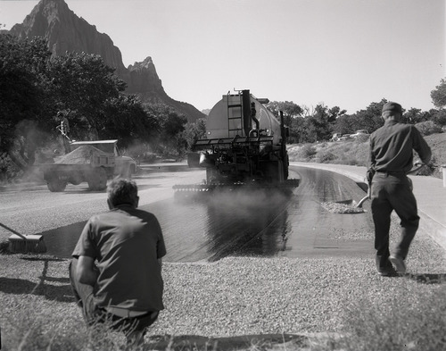 Men operating sealcoating machine while sealcoating parking area in Zion.