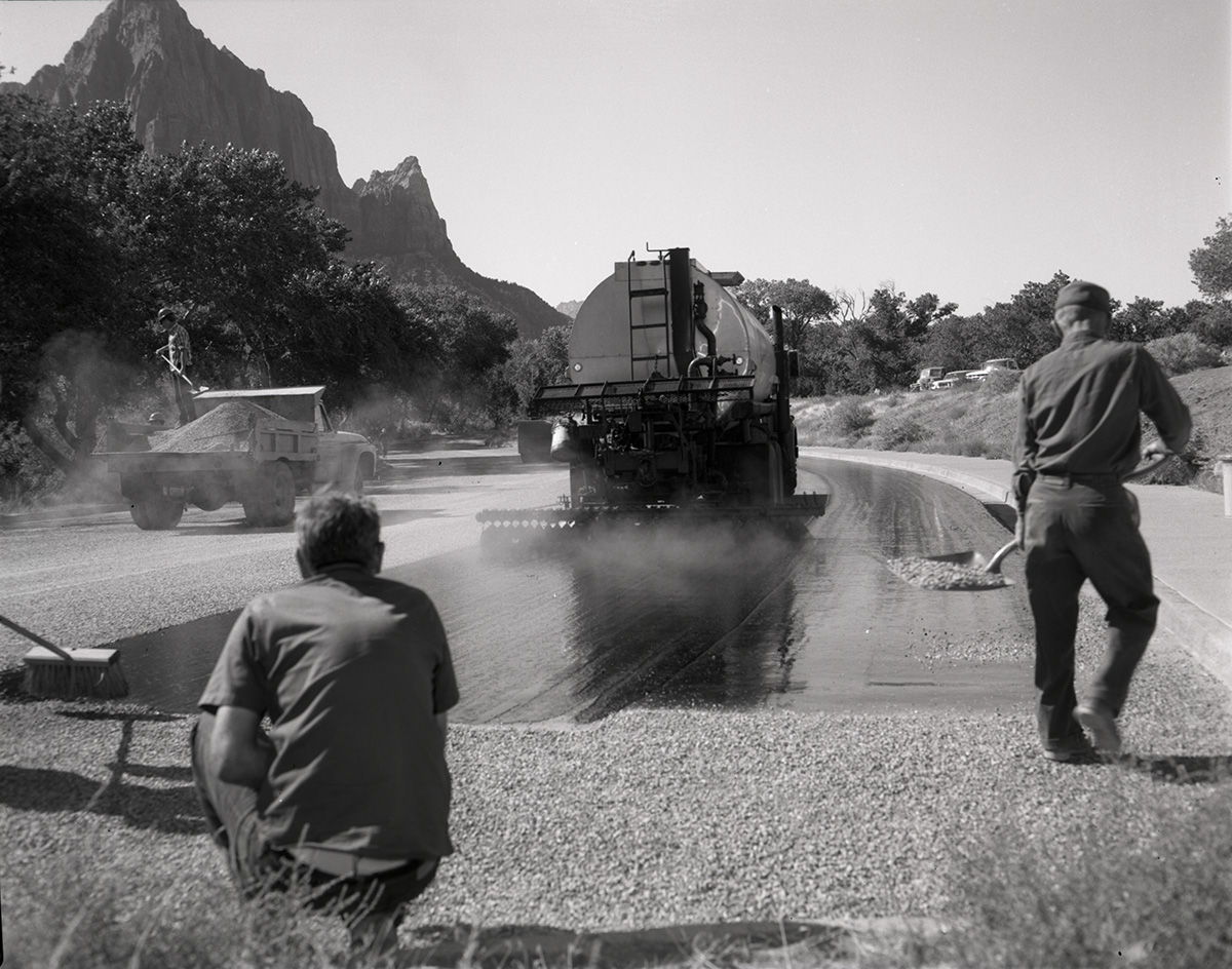 Men operating sealcoating machine while sealcoating parking area in Zion.