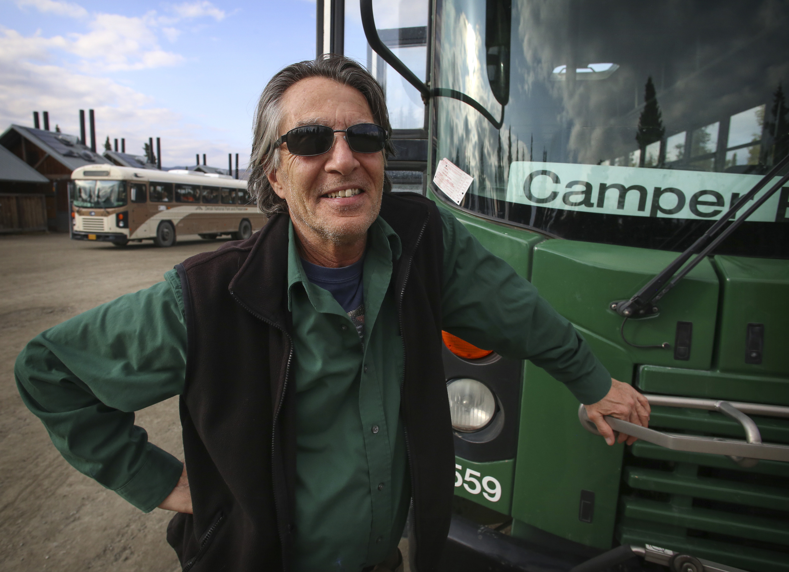 a man standing outside, next to a bus