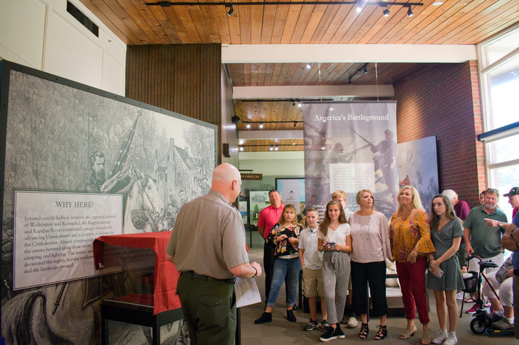 A Park Ranger speaking in front of a group of people in a visitor center.