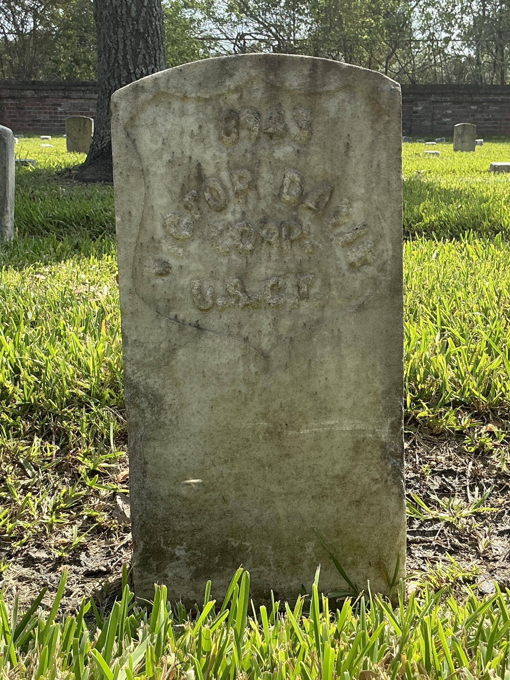 Front of historic upright marble headstone with recessed shield with recessed lettering face.