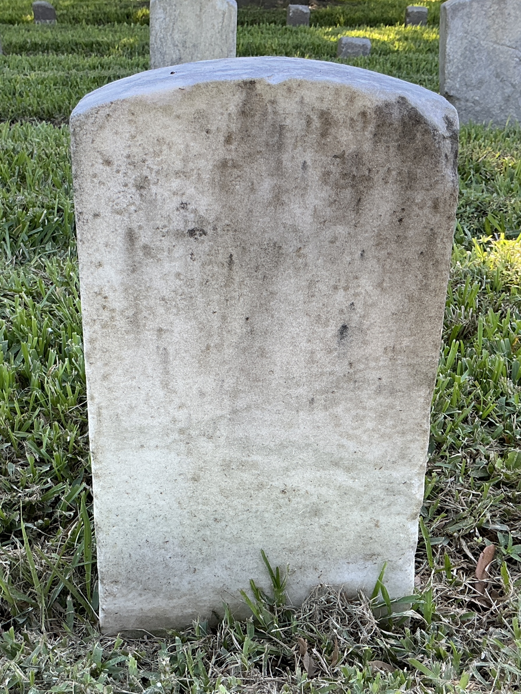 Back of historic upright marble headstone with recessed shield face.