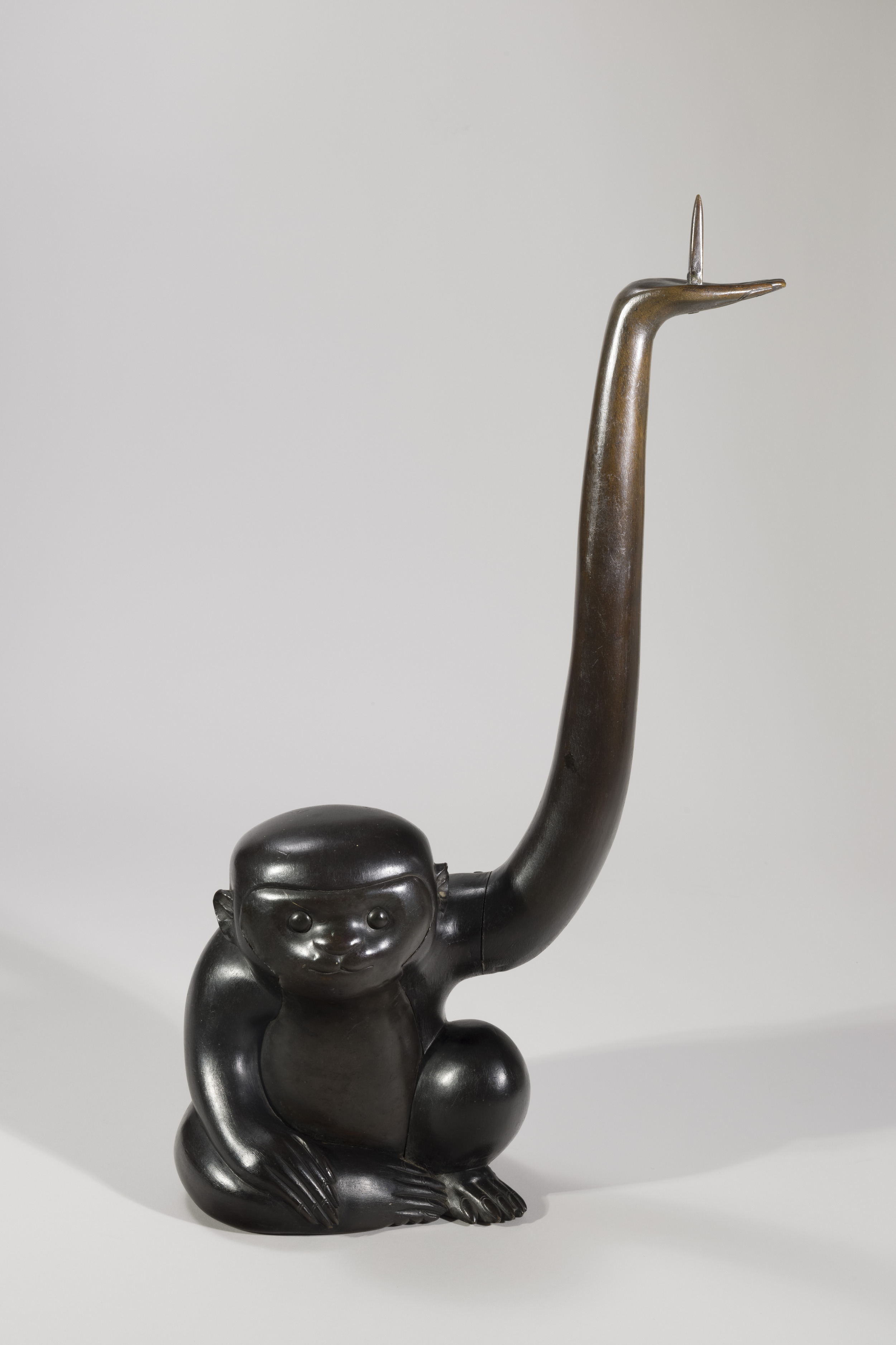 Bronze monkey with raised elongated left arm with spike on palm.