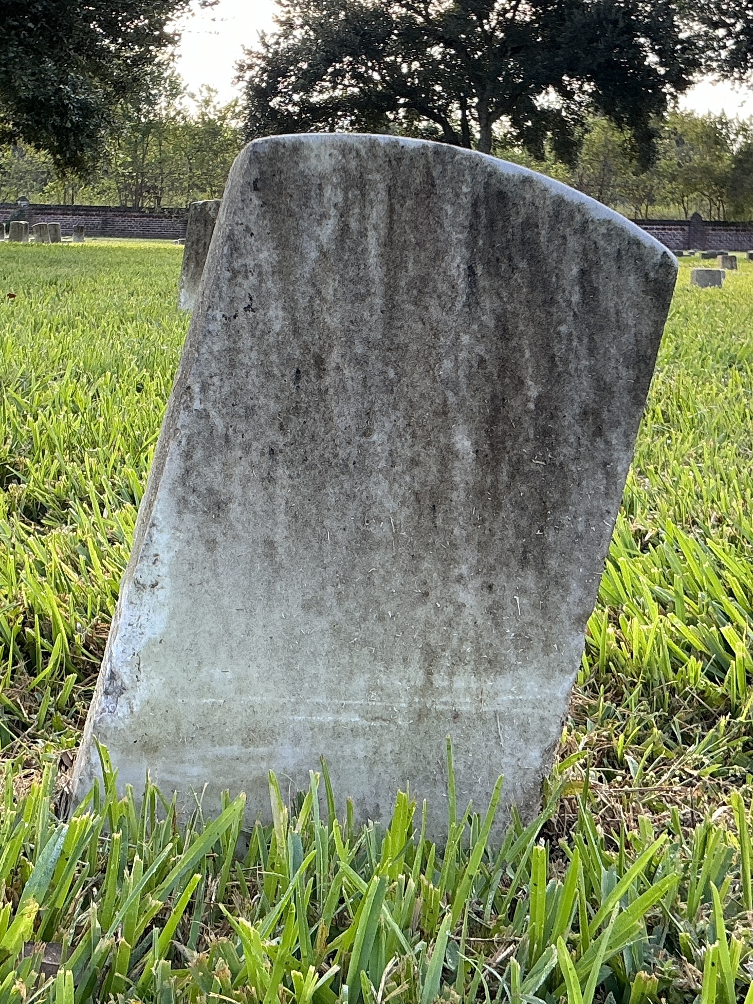 Back of historic upright marble headstone with recessed shield face.