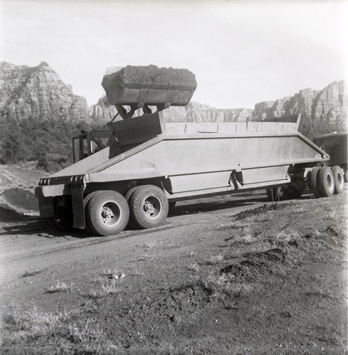 Excavator dumping pile of dirt into back of construction truck during road grading to Chamberlain Ranch and the Narrows.