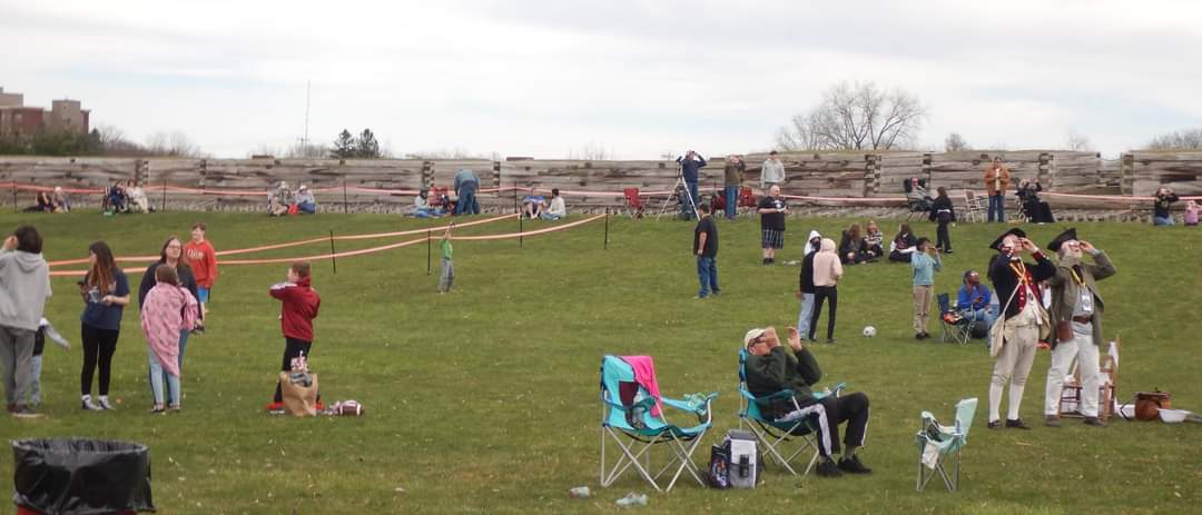 A few hundred people scatter themselves over the park lawn. They are all staring up at the sky with special viewers and glasses covering their faces. 