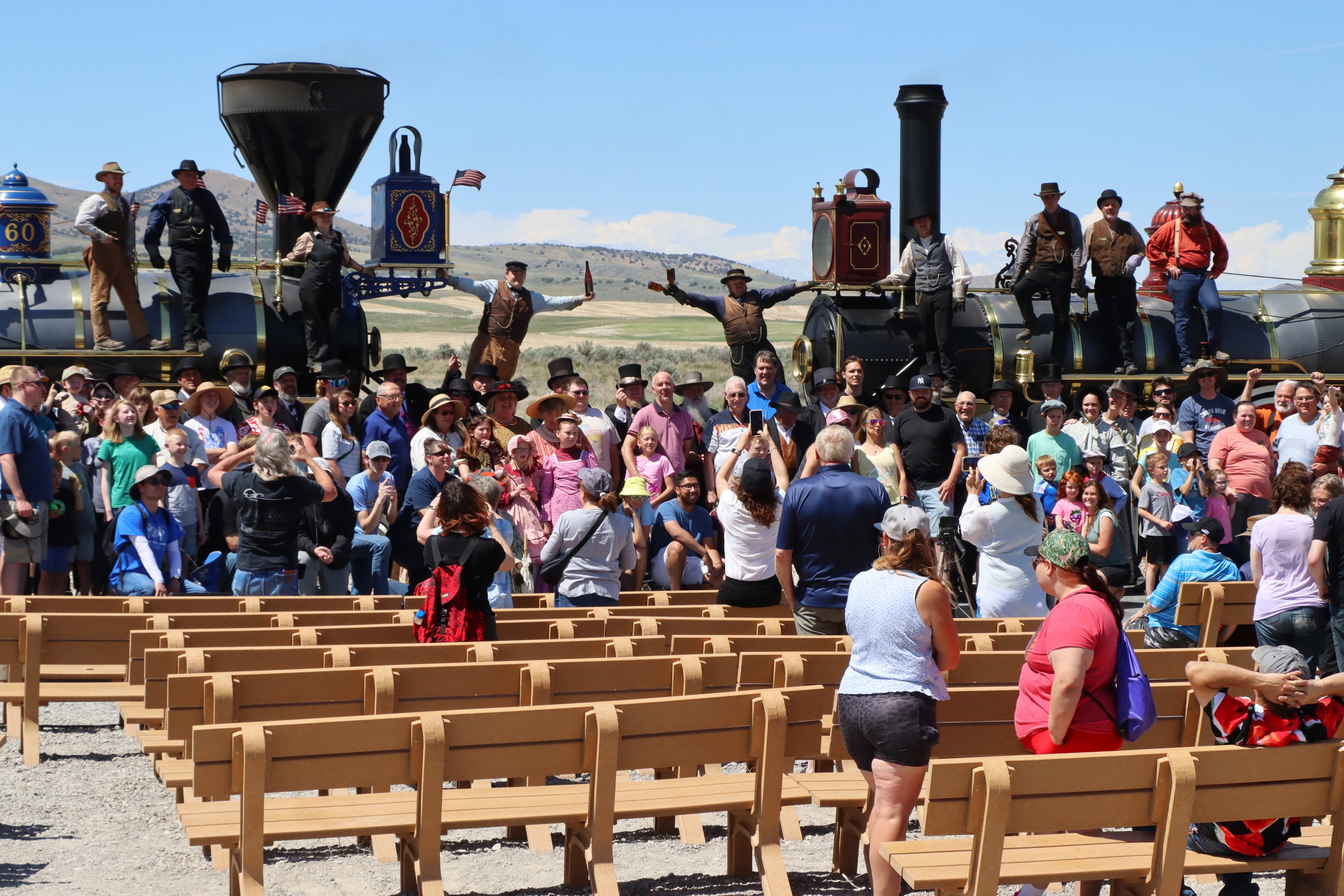 People gathered around two vintage Locomotives to recreate the Historical Champagne photo.