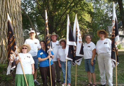 A group of volunteers and a SCA intern holding flags for the 150th Anniversary of the Homestead Act.