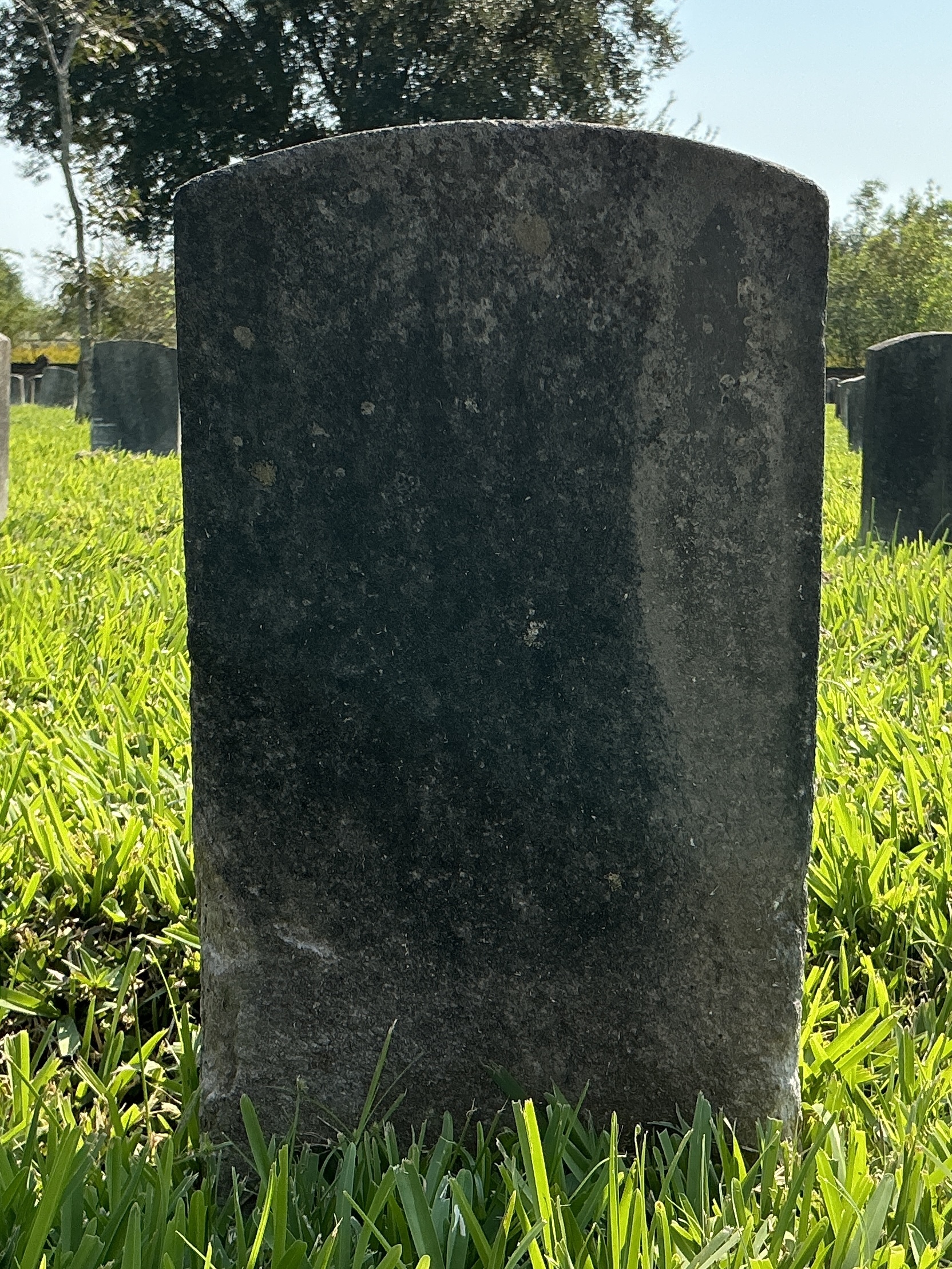 Back of historic upright marble headstone with recessed shield face.