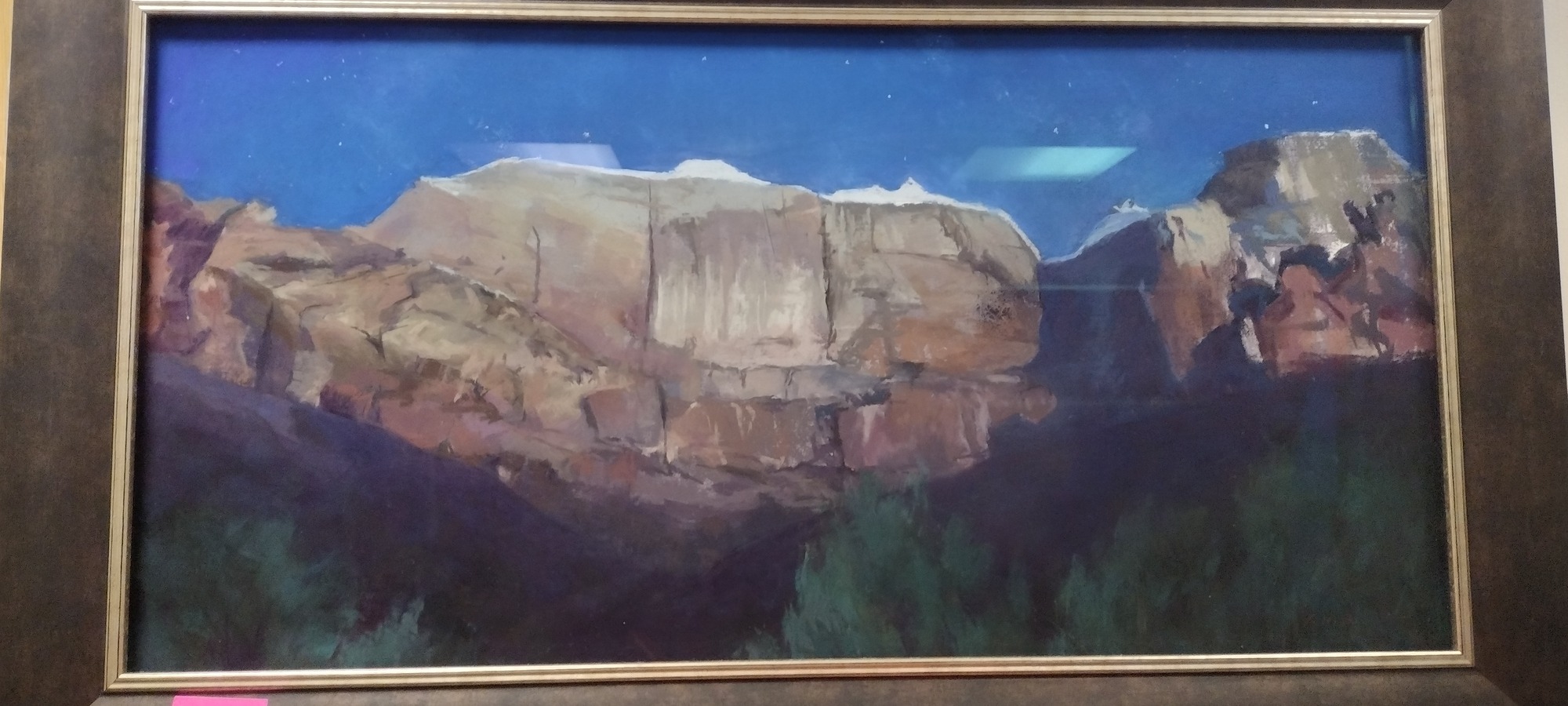 A painting depicting moonlit sandstone cliffs near the Sentinel summit in Zion Canyon. The cliffs are topped with white snow, which glows in the moonlight. Below, the pale sandstone turns to earthy oranges and browns, before fading into the shadows of the canyon.