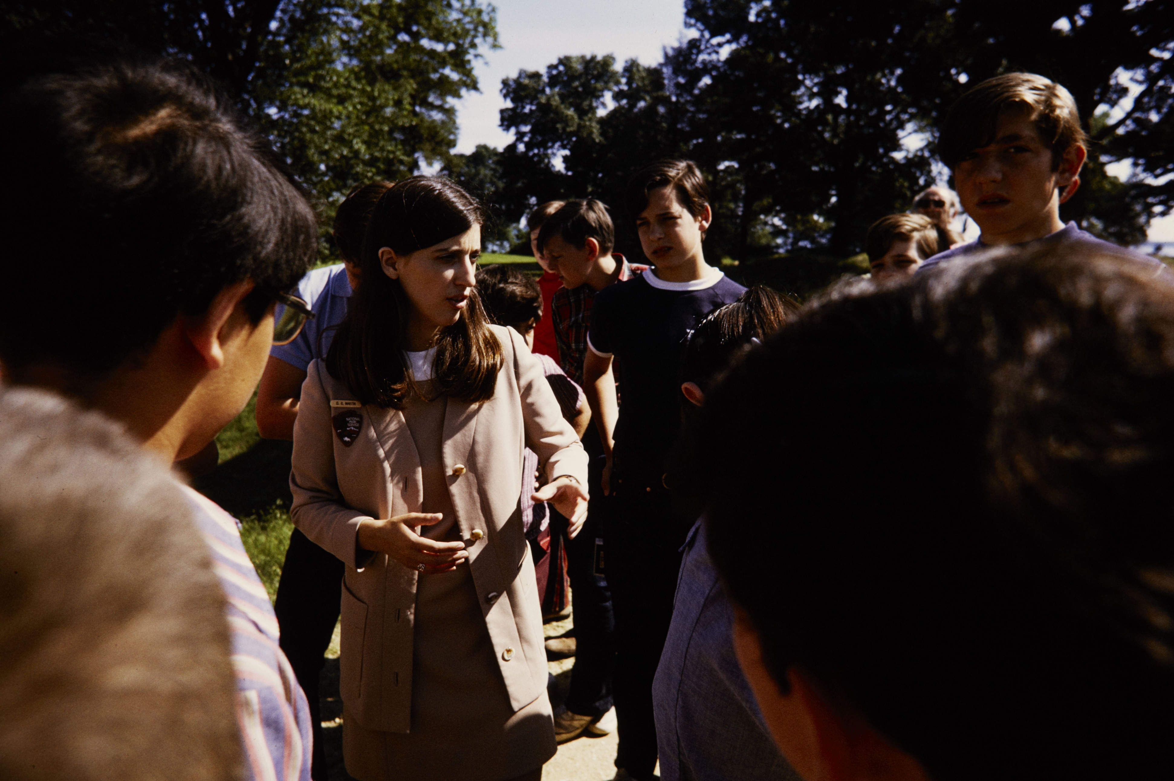 O.C. Martin in her NPS uniform stands talking in the middle of a group of visitors. 